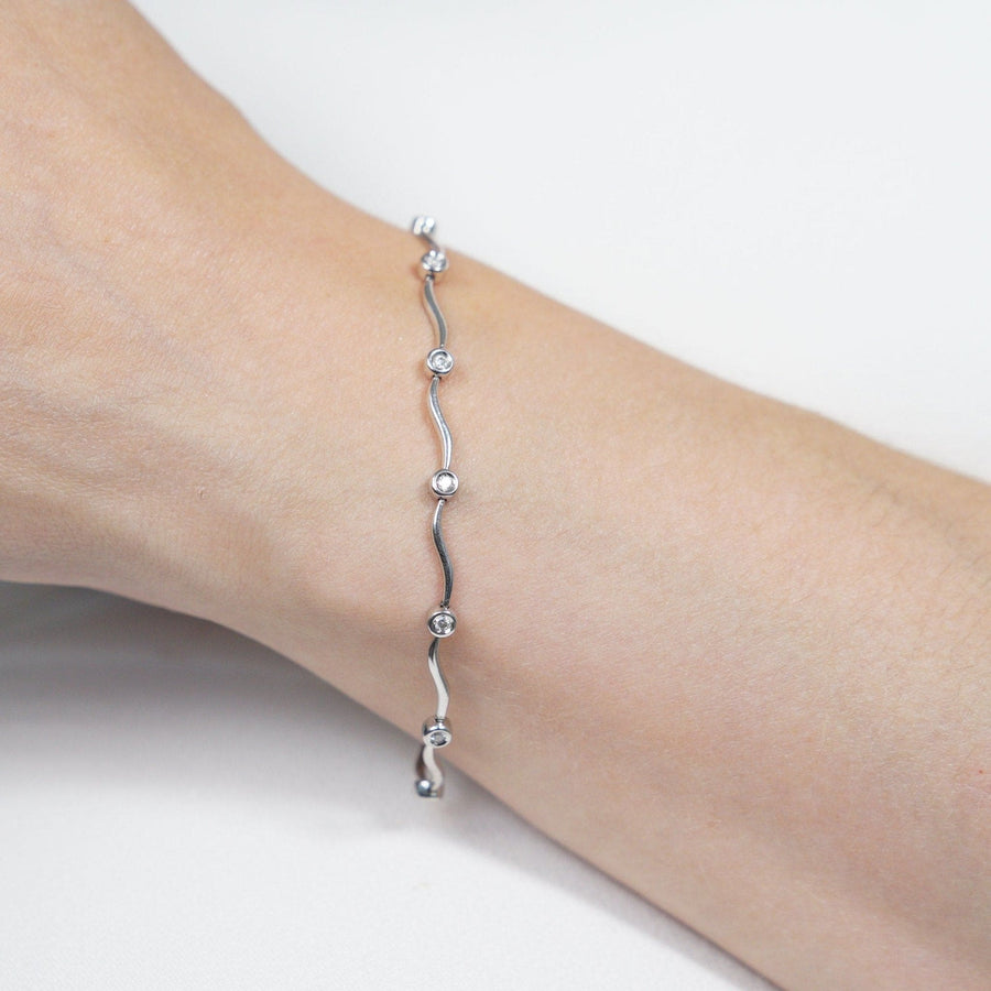 Stilvolles, modernes, gewelltes Diamantarmband aus 9 Karat Weißgold am Handgelenk zeigt elegantes Design mit funkelnden Diamanten.