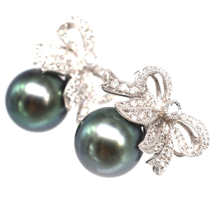 Stilvolle Ohrstecker mit Diamantschleife und schwarzen Tahiti-Zuchtperlen, die einen schicken und zeitlosen Look bieten.