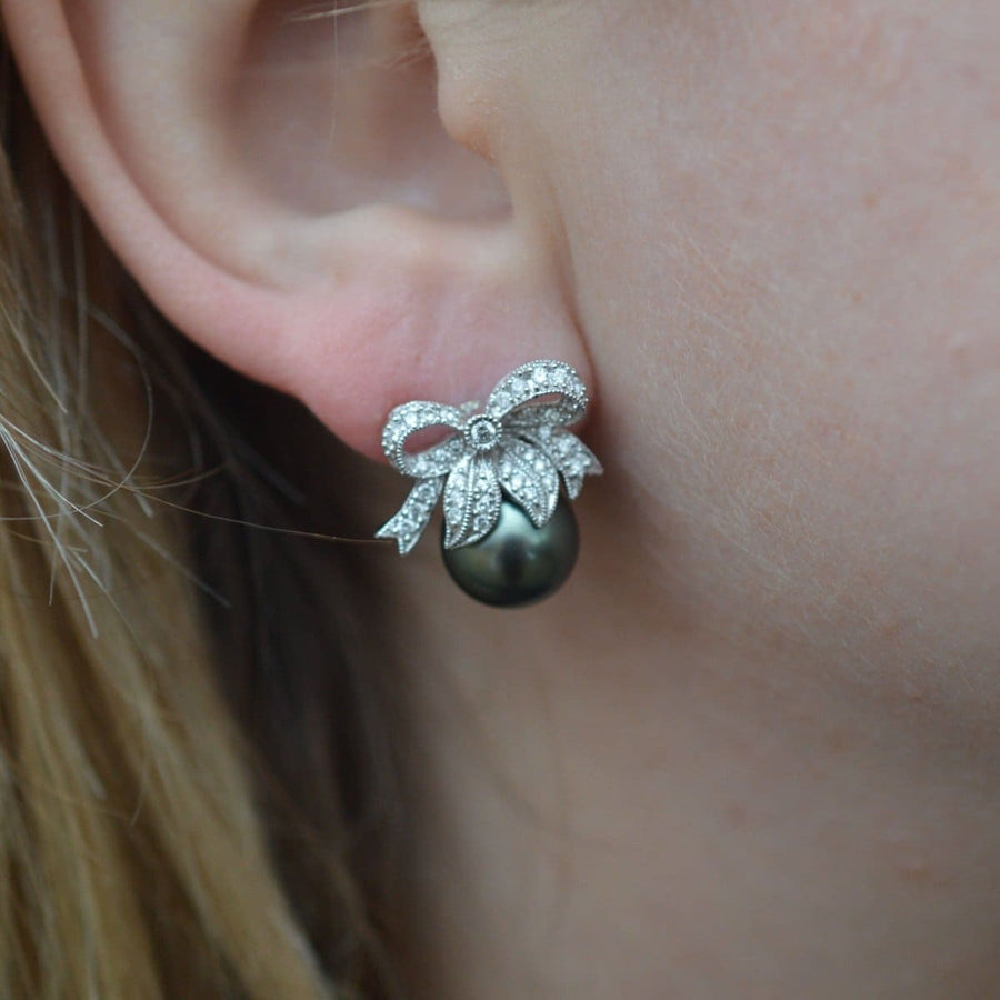 Moderne Ohrstecker mit Diamantschleife und schwarzer Tahiti-Perle, die Eleganz und zeitlosen Stil versprühen.