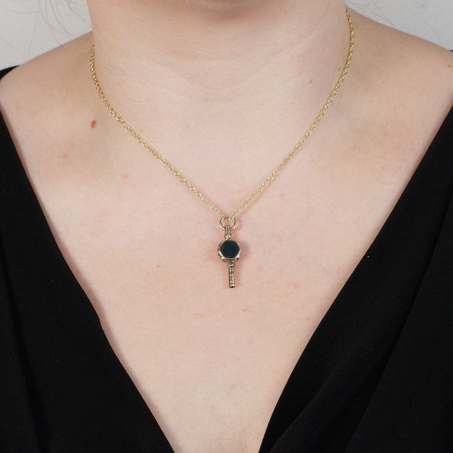 Schlüsselanhänger aus Gold mit Blutstein und Amethyst, der als Schmuck am Hals eines Modells getragen wird.