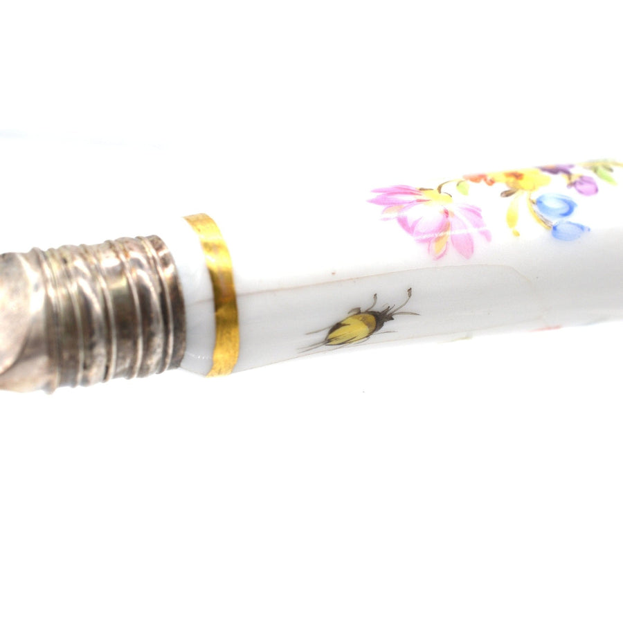 Nahaufnahme eines Besteckgriffs aus Porzellan mit Blumenmotiven und einer gelben Bienenillustration.