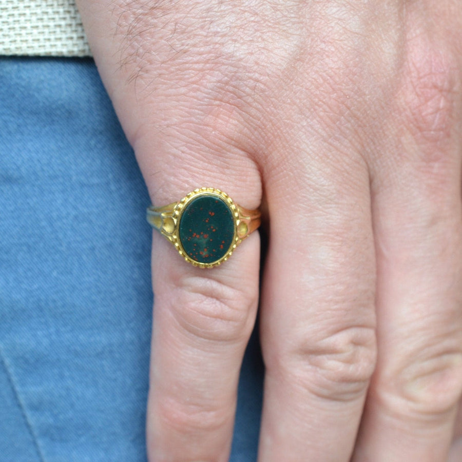 Viktorianischer Siegelring aus 18-karätigem Gold mit Blutstein an einer Hand, der sein verziertes Design und den lebendigen Stein zur Geltung bringt.