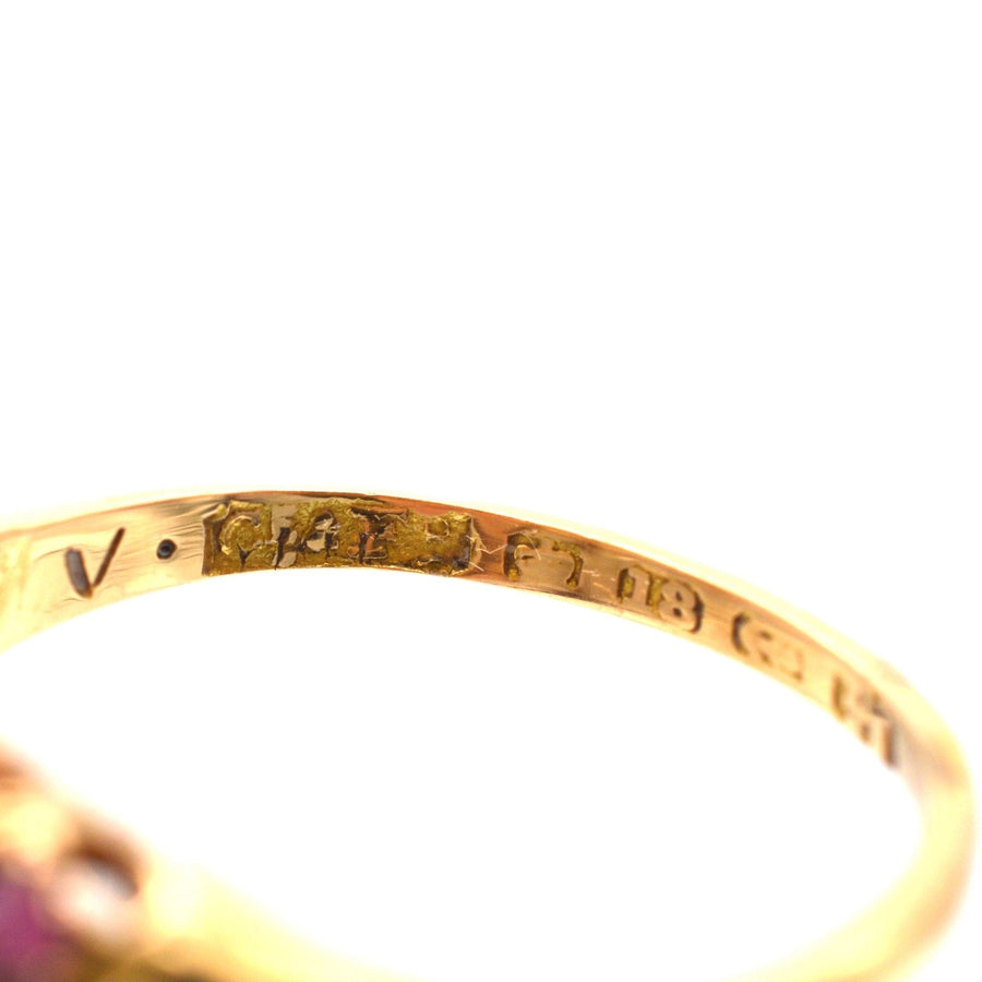 Nahaufnahme der Punzierungen auf einem viktorianischen Ring aus 18 Karat Gold mit Rubin und Diamanten, der seine feine Handwerkskunst unter Beweis stellt.