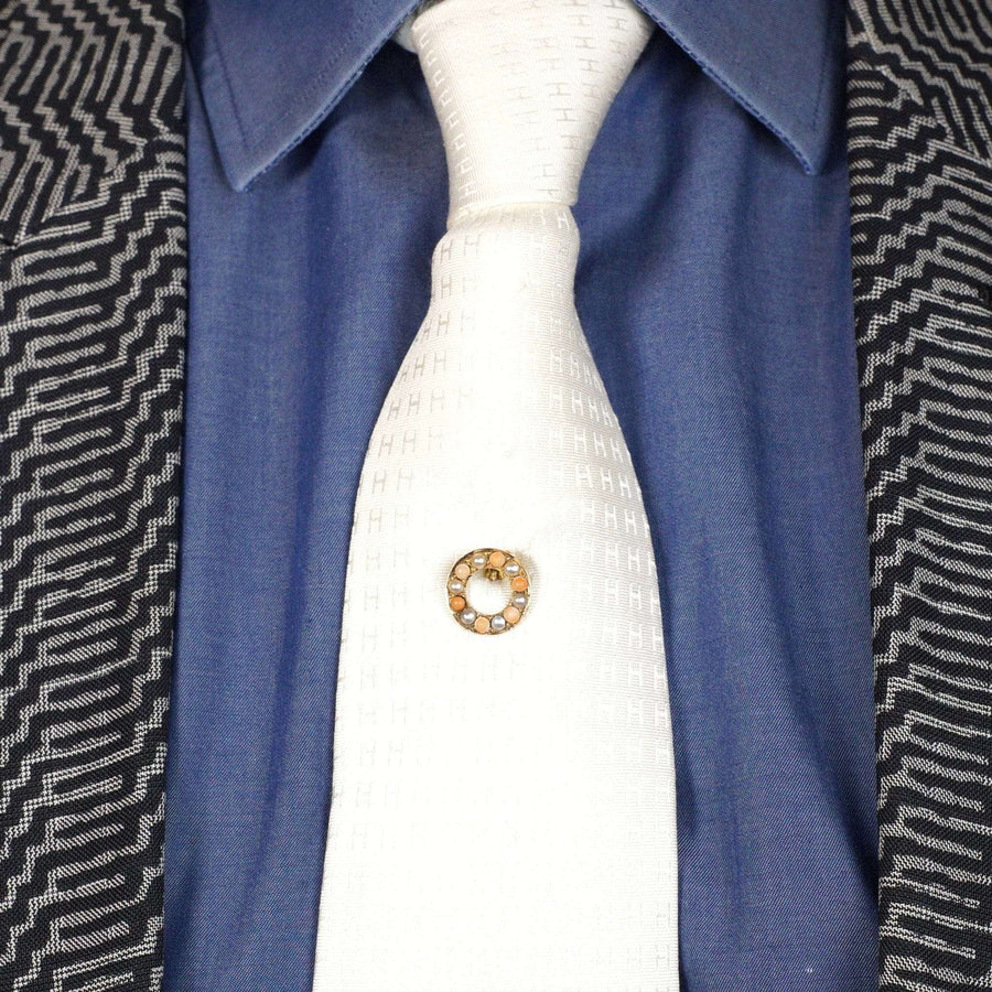Victorian 18ct gold tie pin featuring coral and split pearl on a white tie against a blue shirt.