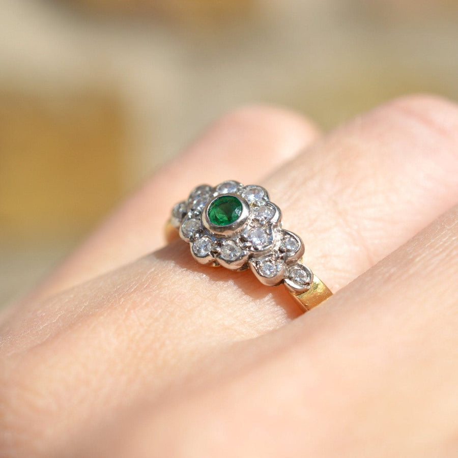 Vintage 18ct Gold Smaragd und Diamant-Cluster-Ring an einer Hand getragen, präsentiert den grünen Smaragd und funkelnden Diamanten.