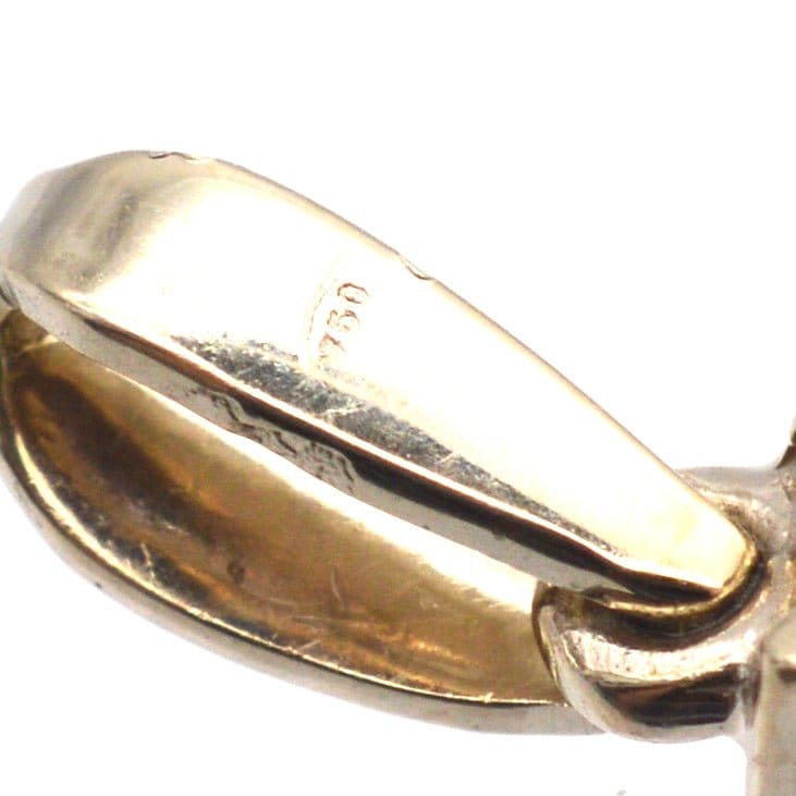 Nahaufnahme eines Anhängers aus Weißgold mit 18-karätiger Punzierung, die Handwerkskunst und Qualität unterstreicht.