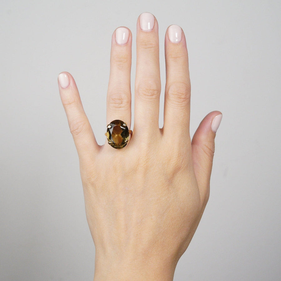 Cocktailring aus 9-karätigem Gold mit Rauchquarz an der Hand einer Frau, der sein kühnes Design und seinen reichen Edelstein zur Geltung bringt.