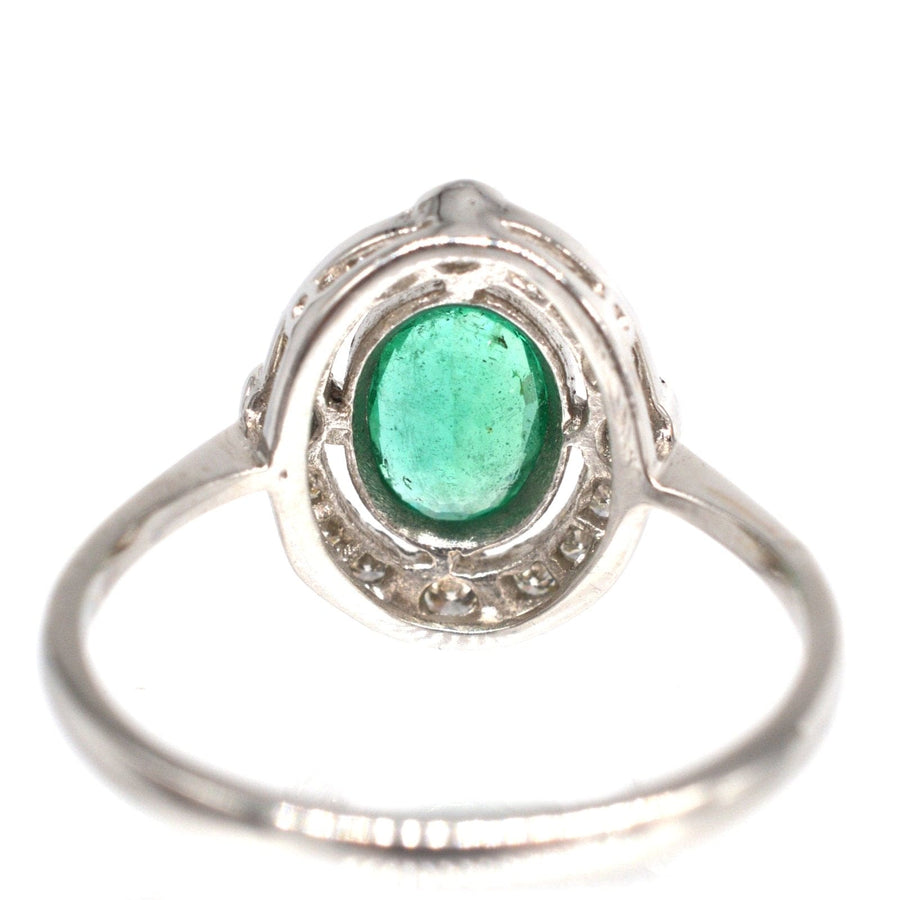 Smaragdring aus Platin im Vintage-Stil mit einem ovalen Smaragd in der Mitte, umgeben von einem Diamantcluster, perfekt für eine Verlobung.