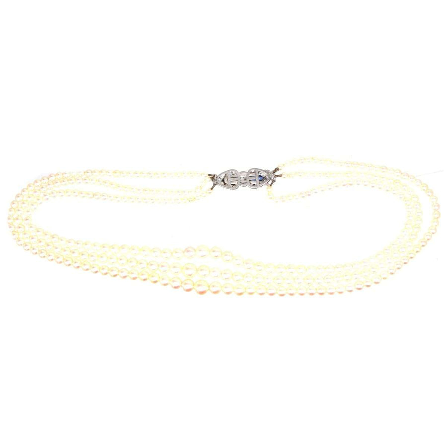 1940s cultured pearl triple strand necklace with sapphire and diamond clasp on a white background.