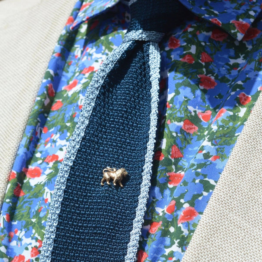 1950s vintage 9ct gold lion tie pin on a blue knitted tie, paired with a floral shirt, showcasing elegant menswear style.