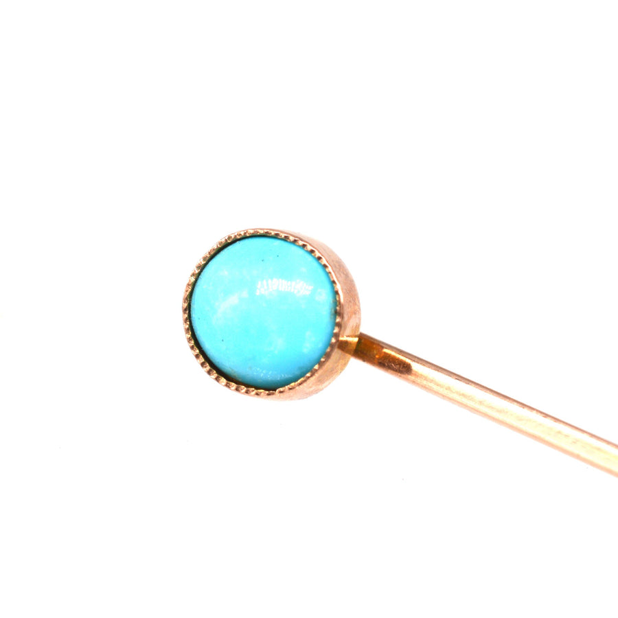 Close-up of an Edwardian 9ct gold tie pin featuring a vibrant turquoise stone in a millegrain setting.