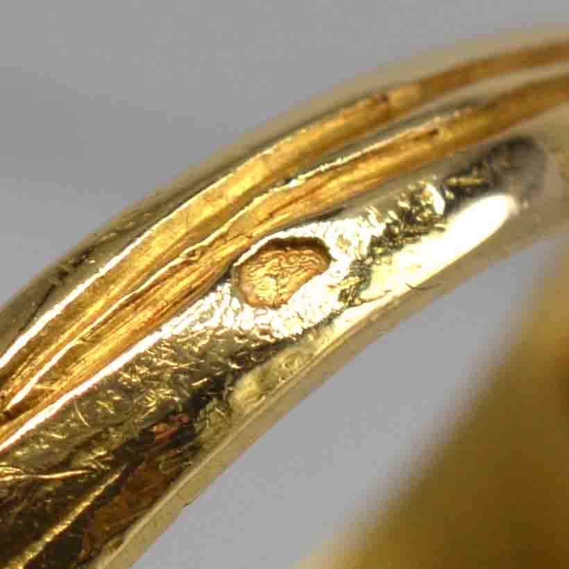 Close-up of the band of an 18ct gold ring, highlighting intricate details and craftsmanship.