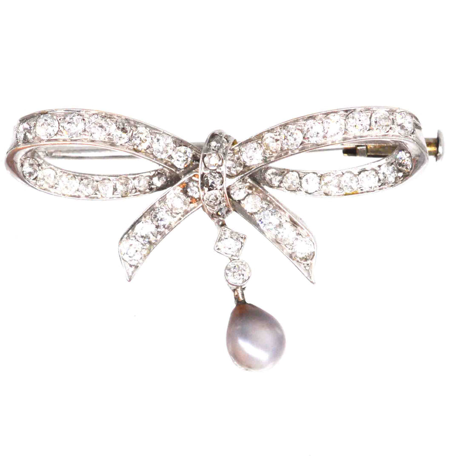 Early 20th century 14ct white gold bow brooch featuring diamonds and a gray pearl pendant, elegant and versatile jewelry.