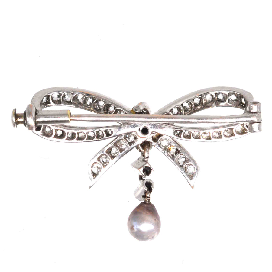 Early 20th century white gold bow brooch with diamonds and gray pearl, stylish and versatile accessory.