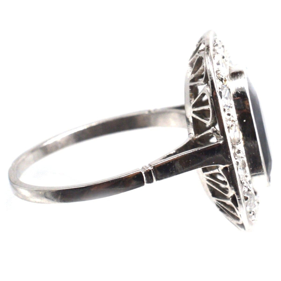 Art Deco French platinum ring featuring a dark sapphire and diamond cluster, showcasing intricate detailing and elegance.