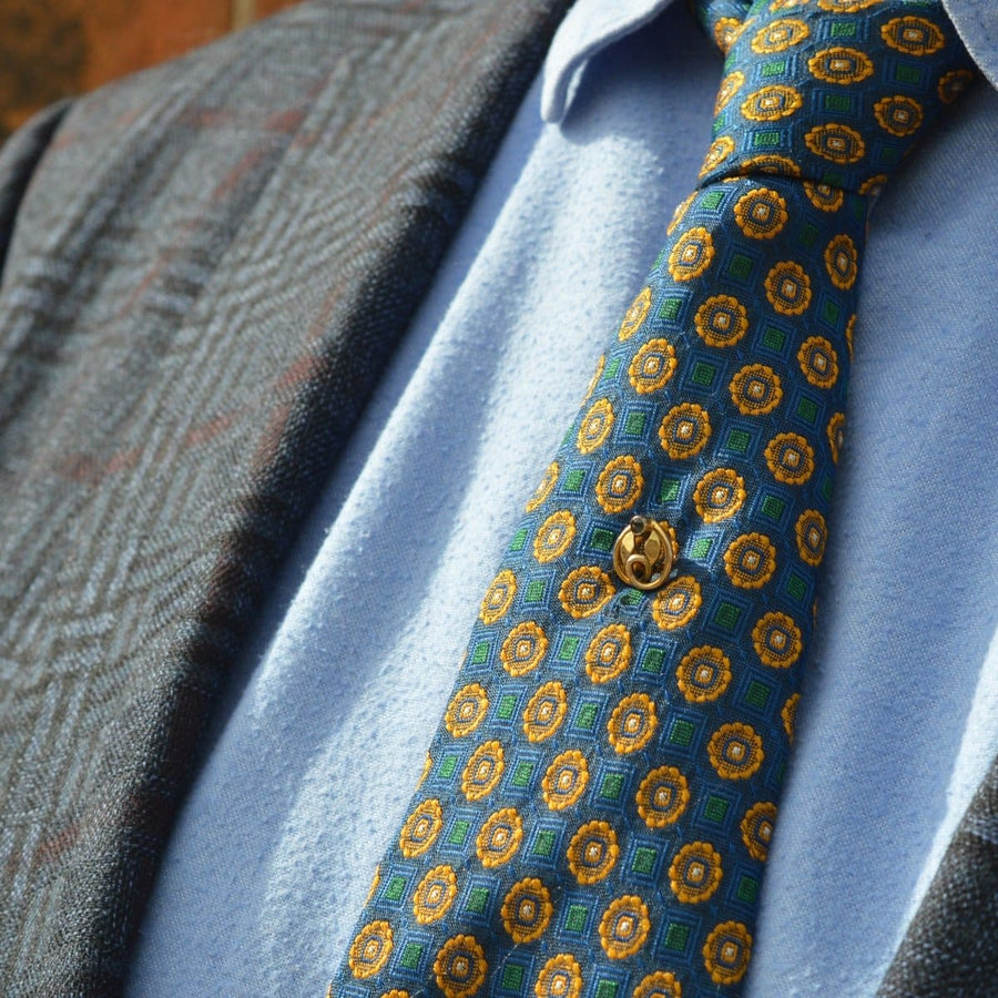 Art Nouveau tie pin featuring a green garnet doublet, accentuated by a gold leaf on a patterned tie.