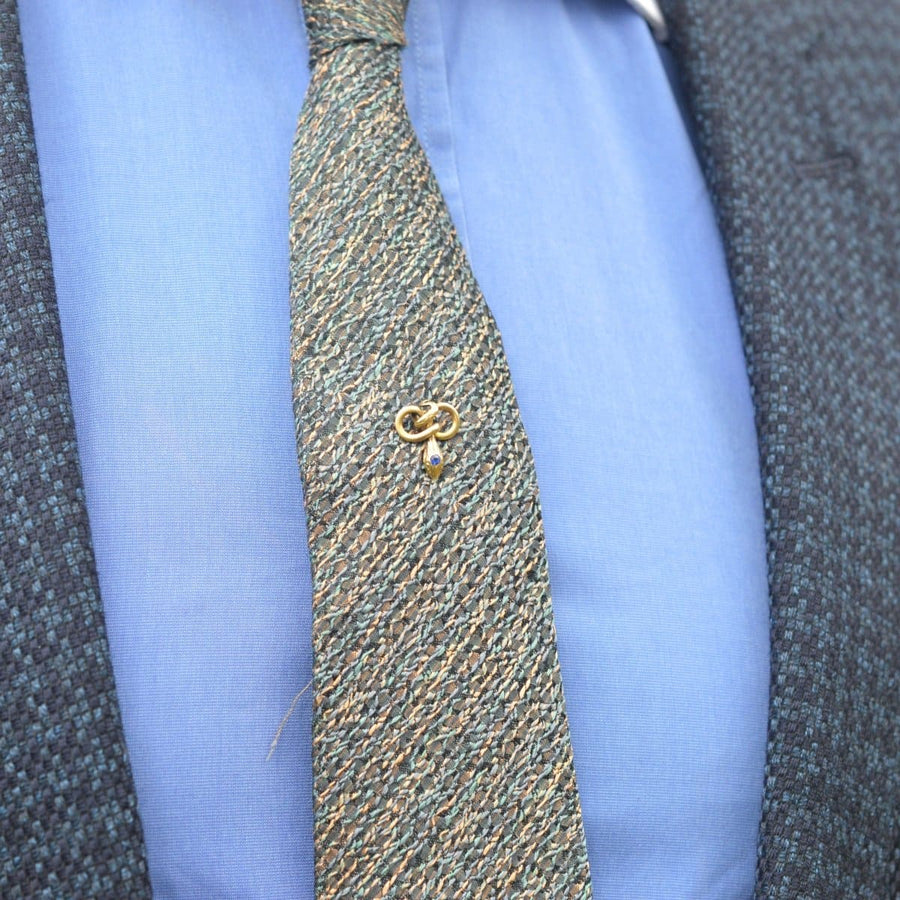 Art Nouveau gold snake tie pin with blue paste, elegantly displayed on a textured tie and shirt.