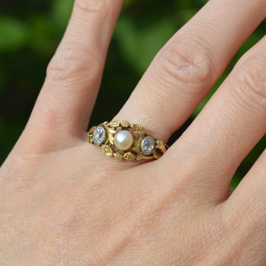 Art Nouveau 18ct gold ring featuring natural pearl and old mine cut diamonds on a hand.