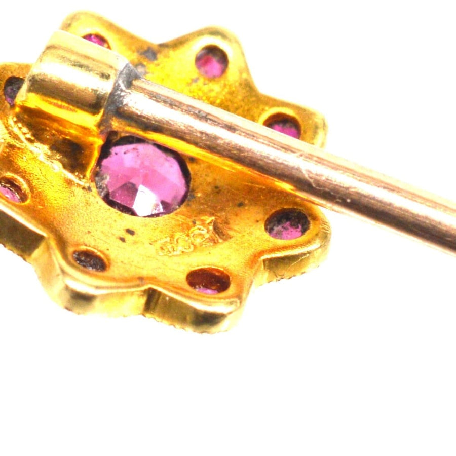 Close-up of an Edwardian gold tie pin with garnet and seed pearl cluster design, showcasing intricate craftsmanship.
