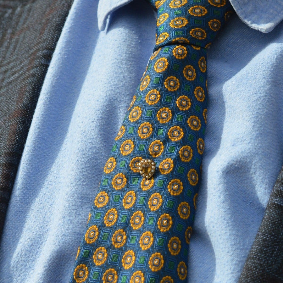 Edwardian 9ct gold heart tie pin with citrine and seed pearls, styled on a patterned tie.