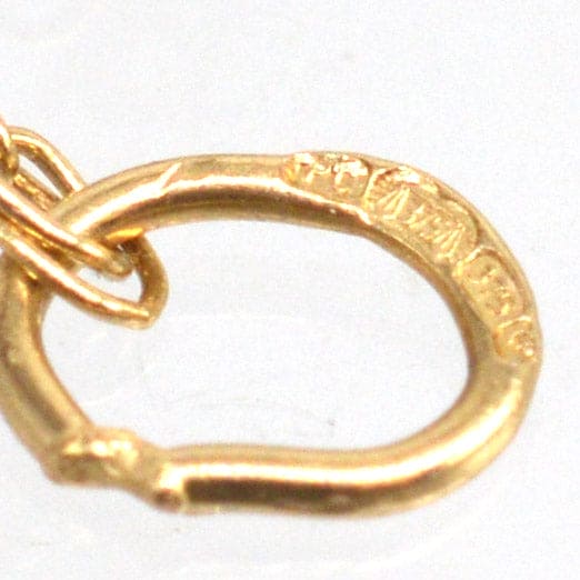 Close-up of a gold pendant loop showcasing fine craftsmanship and stamp details.