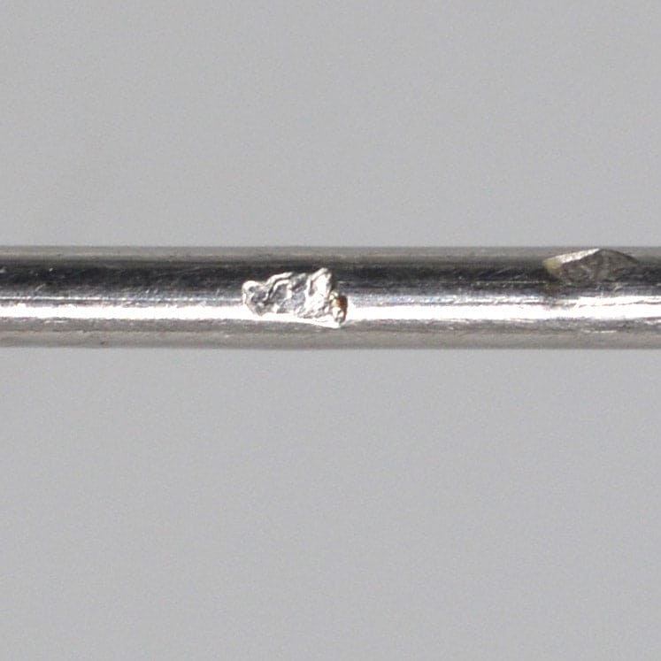 Close-up image of a silver metal rod showing surface imperfections and scratches.