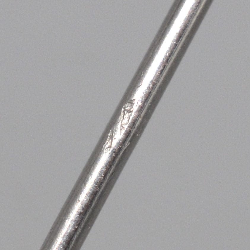 Close-up of a silver metal bar with surface imperfections and scratches, highlighting its texture and details.