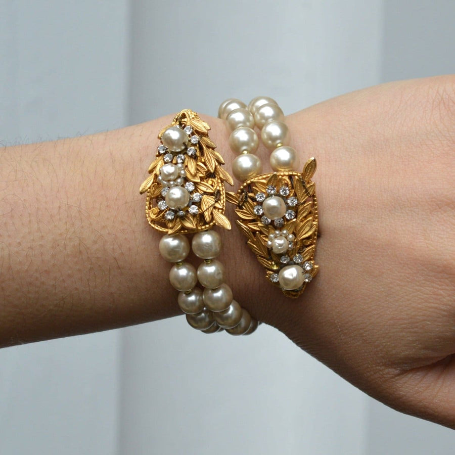 Miriam Haskell gold metal serpent bangle with white paste and faux pearl clusters on wrist.