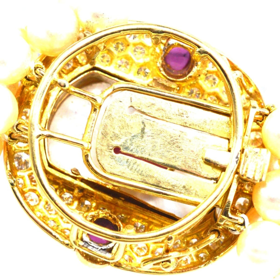 Close-up of a vintage French gold clasp featuring rubies and rock crystal on a cultured pearl necklace.