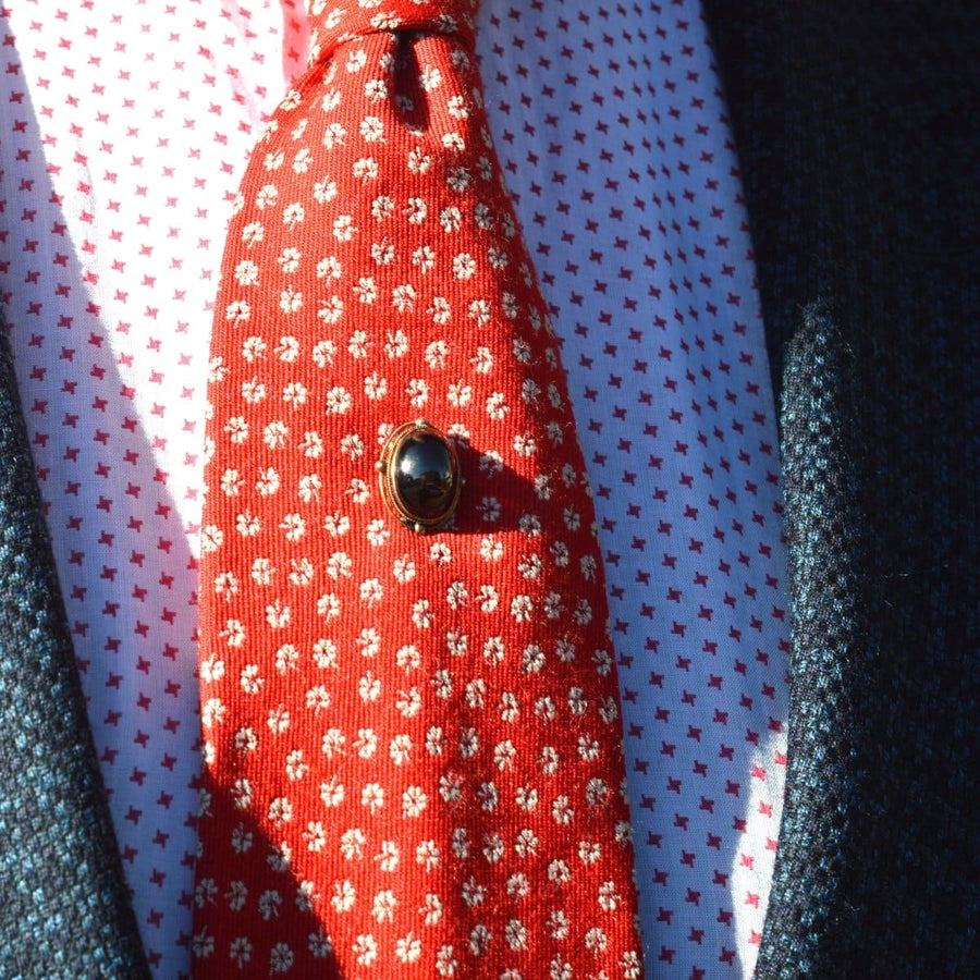 Victorian 15ct gold cabochon garnet tie pin on a patterned red tie, showcasing timeless elegance and rich color.