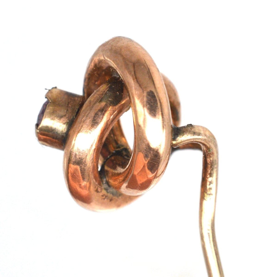 Victorian gold knot tie pin with garnet center, symbolizing the lover's knot, vintage jewelry piece from the 1880s.