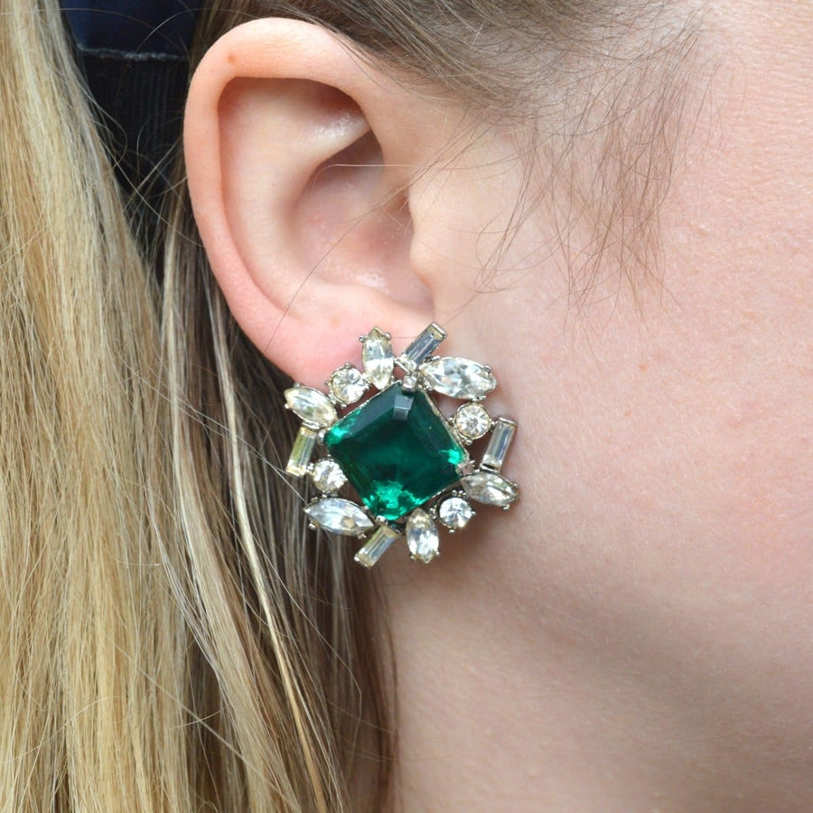 Vintage 1990s Kenneth Lane green and white paste clip-on earrings worn, showcasing a large green stone with a sparkling cluster.