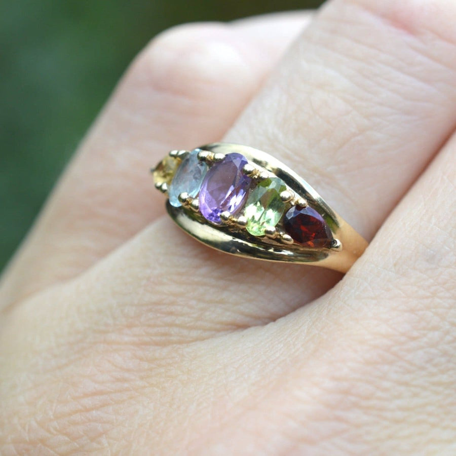 Vintage 9ct gold multi gem ring showcasing citrine, aquamarine, amethyst, peridot, and garnet on a hand.