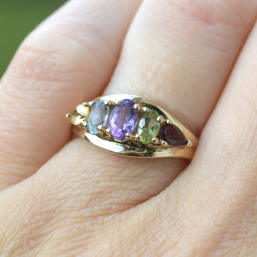 Vintage 9ct gold multi-gem five stone ring with citrine, amethyst, aquamarine, peridot, and garnet on a hand.