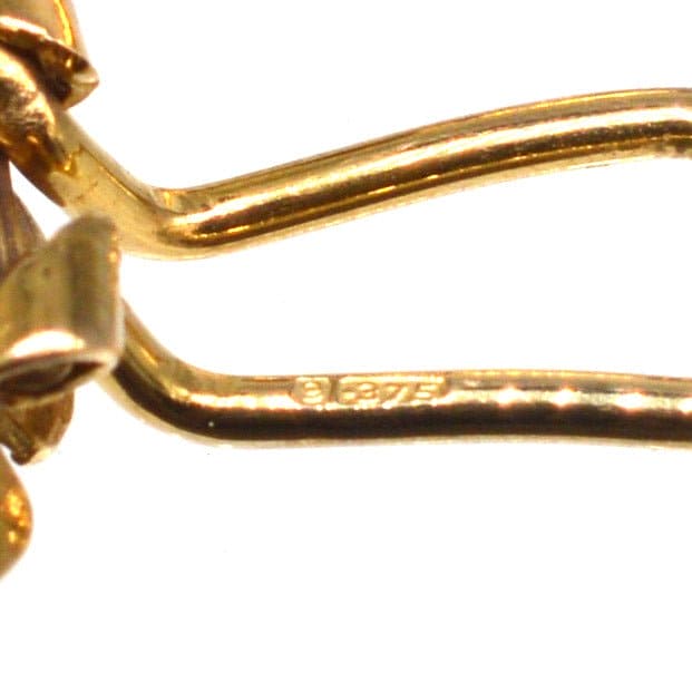 Close-up of 1940s 9ct gold flower clip-on earrings showcasing stamp detail.