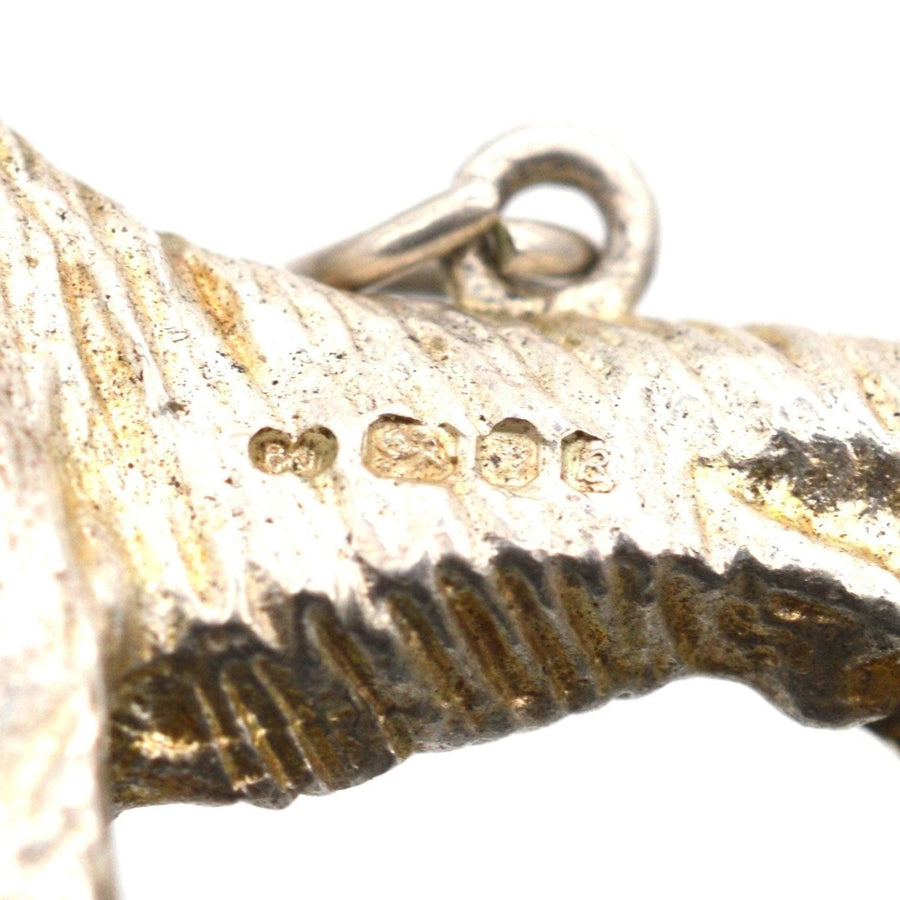 Close-up of a 1970s silver dog pendant showing detailed craftsmanship and stamp stamps.