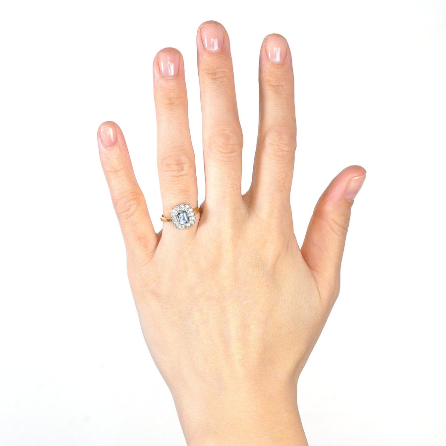Vintage 18ct gold aquamarine and diamond cluster ring worn on a hand, showcasing its elegant design.