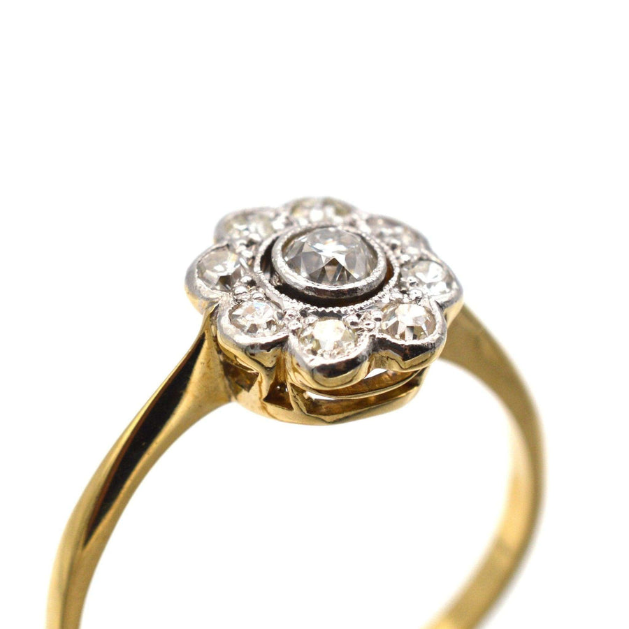 Art Deco 18ct gold and platinum diamond cluster ring, featuring a central 0.10 carat diamond and millegrain setting.