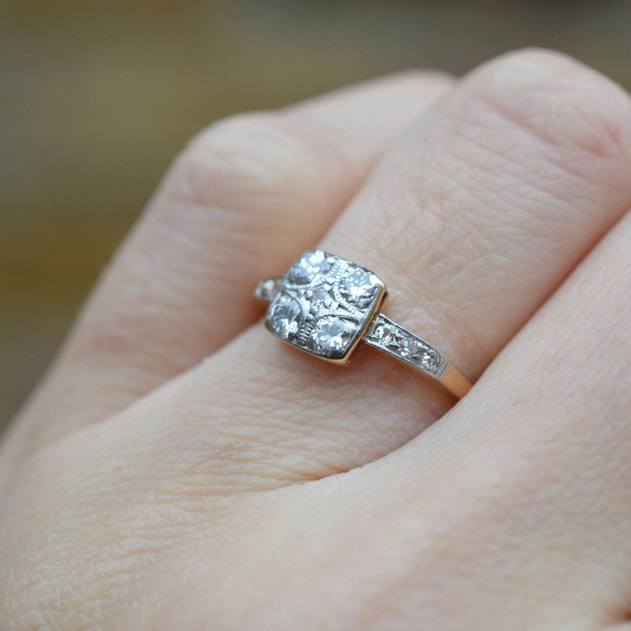 Art Deco 18ct gold and platinum diamond square ring worn on a hand, featuring a unique floral design and shoulder diamonds.