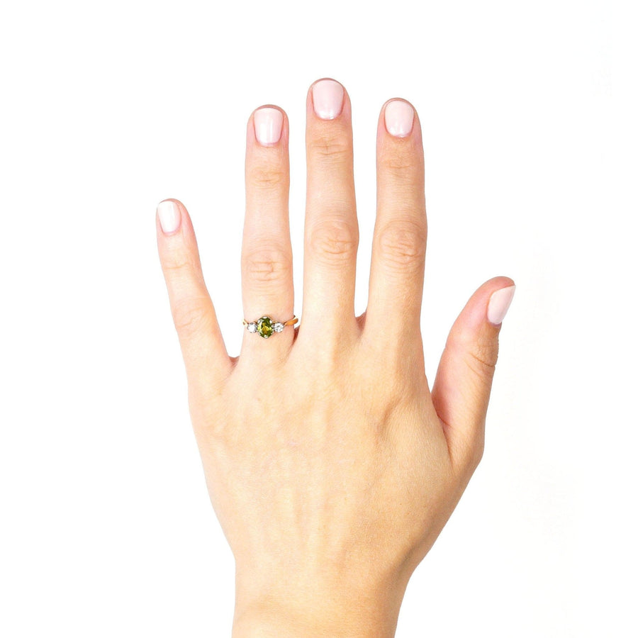 Art Deco 18ct gold and platinum three stone peridot and diamond ring on a hand, showcasing its olive green brilliance.