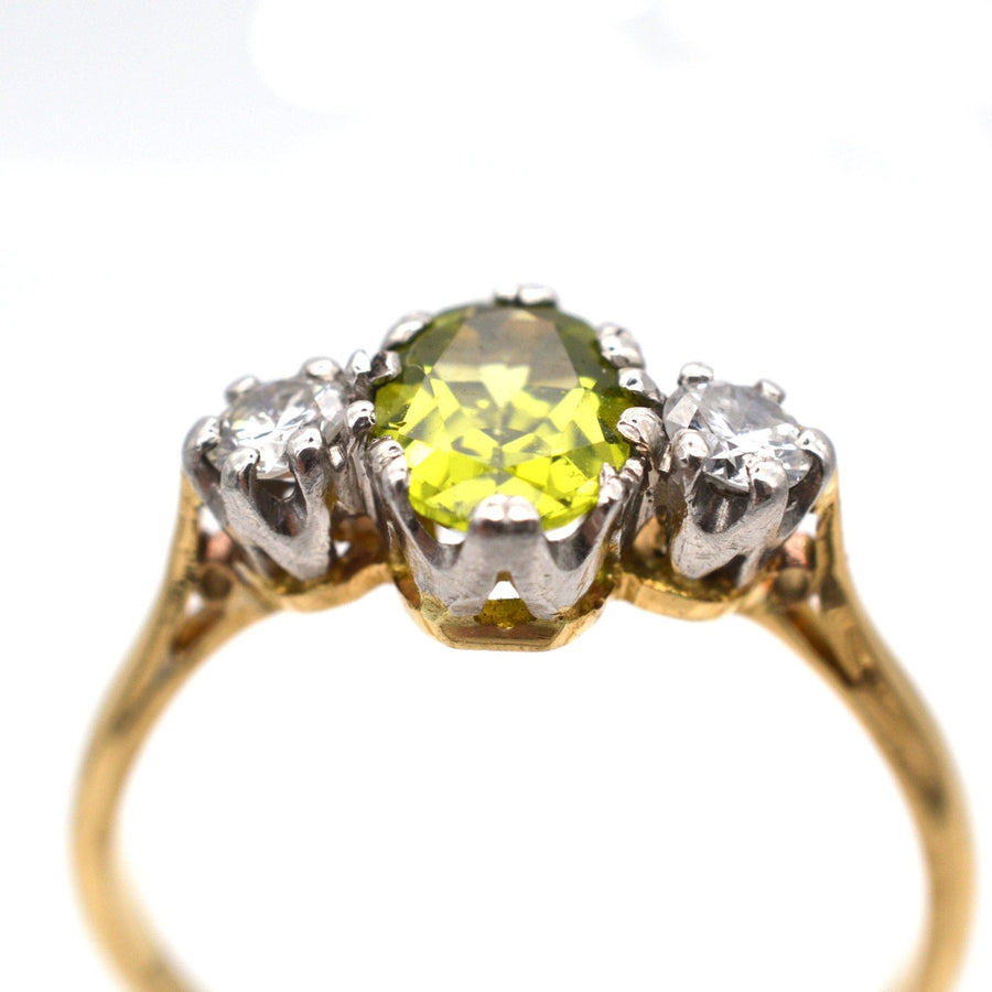 Art Deco 18ct gold and platinum three stone ring featuring central peridot and two diamonds, low-profile design.
