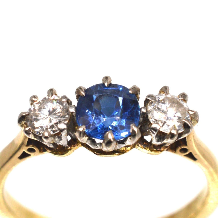 Art Deco 18ct gold three stone ring featuring a vibrant sapphire and diamond accents, perfect for an engagement.