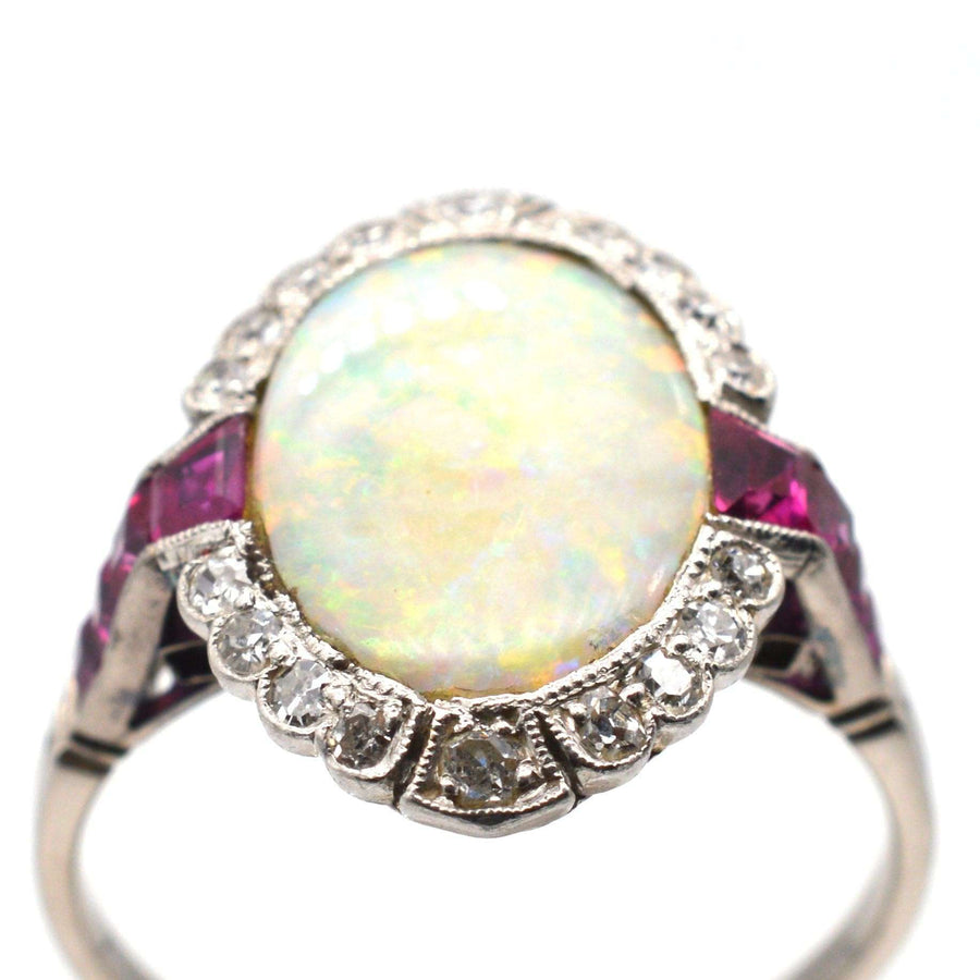 Art Deco 18ct white gold and platinum ring featuring an opal center stone surrounded by Burma rubies and diamonds.