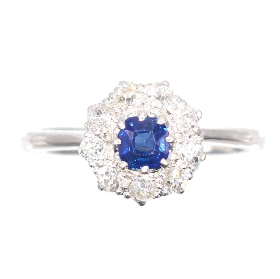 Art Deco 18ct white gold cluster ring featuring a central blue sapphire surrounded by sparkling diamonds.