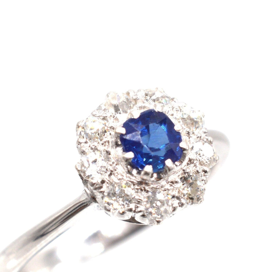 Art Deco 18ct white gold sapphire and diamond cluster ring with a central round sapphire and diamond halo setting.