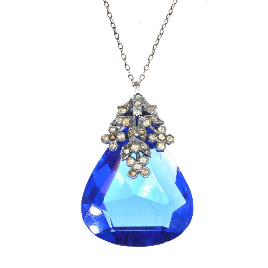 Art Deco blue paste pendant with white floral setting on silver chain, showcasing elegant costume jewelry design.
