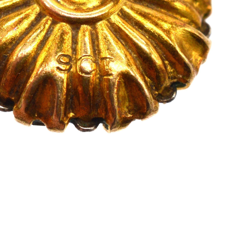 Close-up of 9ct gold stamp on decorative Art Deco earring design with radiant texture.