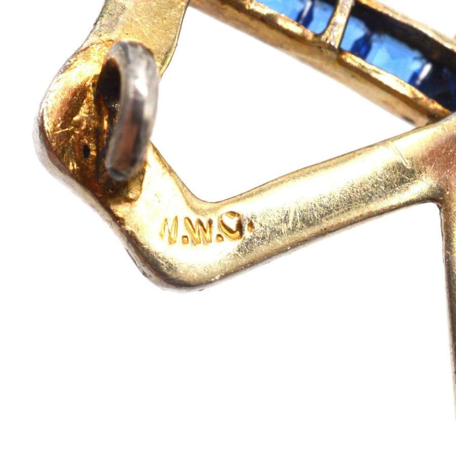 Close-up view of the stamp on an Art Deco brooch featuring blue sapphire paste and gold detailing.