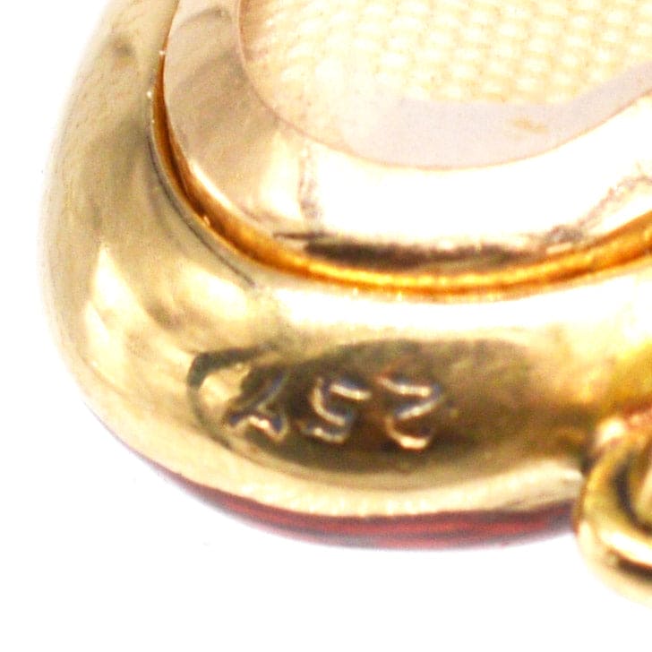 Close-up of Edwardian 18ct gold locket showing stamp detail and rich red enamel finish.