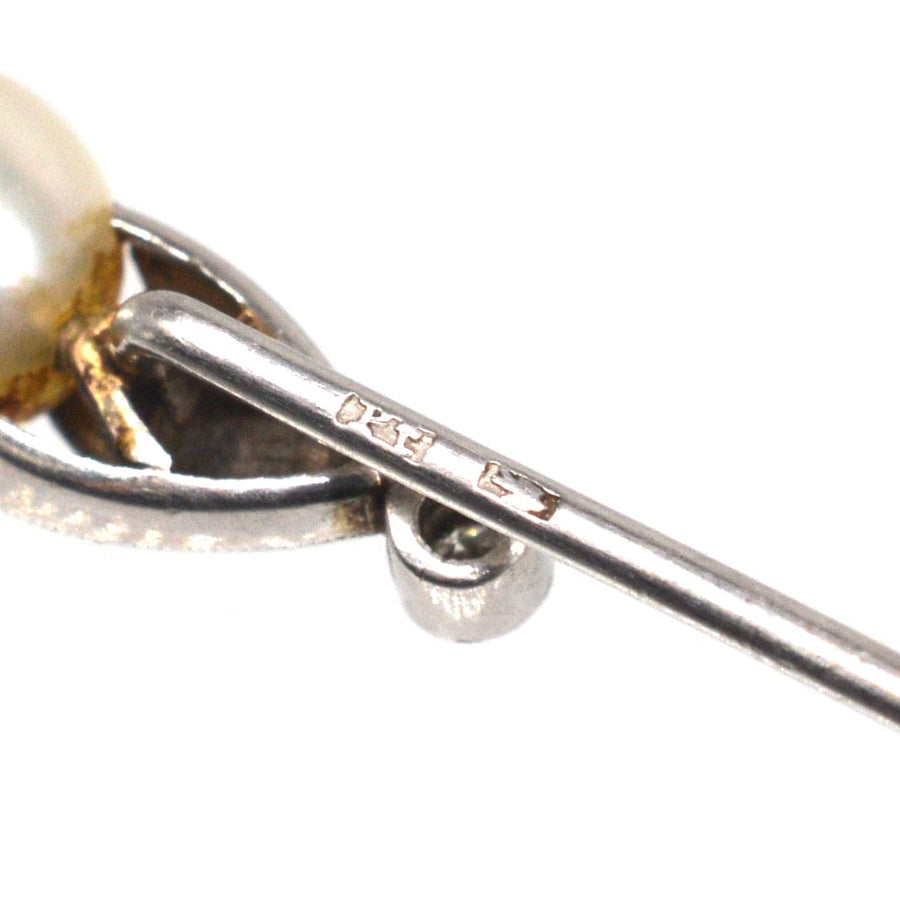 Close-up of an Edwardian natural pearl and diamond platinum tie pin showcasing intricate detailing and stamp.